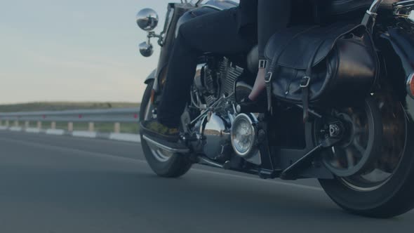 Man and woman riding along road in desert on motorbike, closeup view from below. Couple is riding