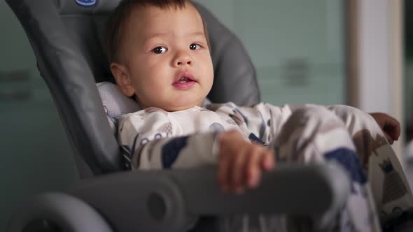 Pensive Asian child sitting in the stroller