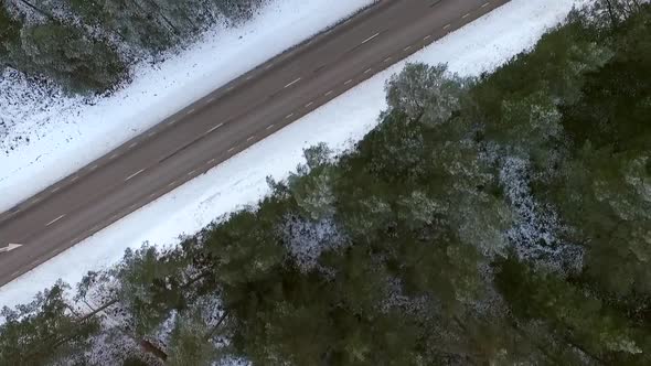 Aerial view of an empty road in the middle of the forest in winter in Estonia.