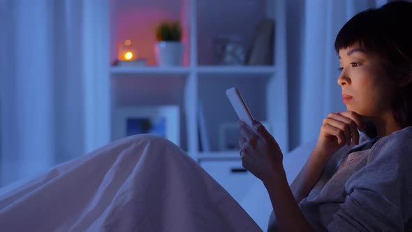 Woman with Smartphone in Bed at Home at Night