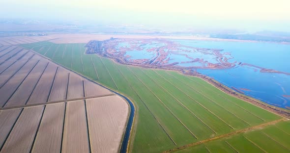 Different Fields of Brown and Green Colours Against Lagoon