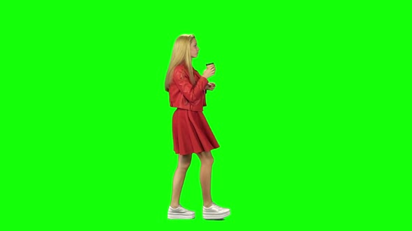 Blonde Girl Calmly Walking and Drinking Coffee on Green Screen. Chroma Key. Profile View. Slow