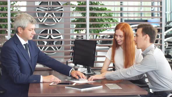 Happy Beautiful Couple Is Buying a New Car at Dealership