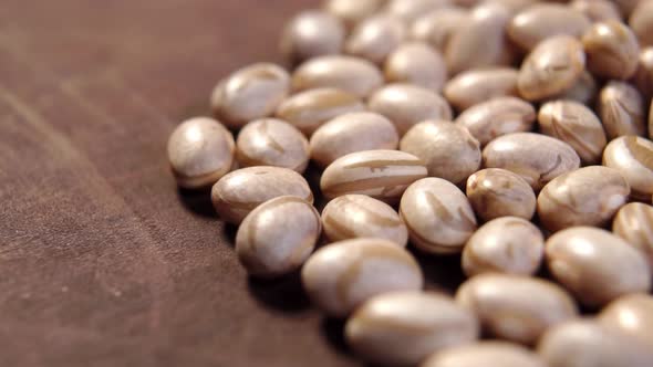 Raw Carioca beans on rustic wooden surface. Brazilian legume grains. Phaseolus vulgaris. Macro