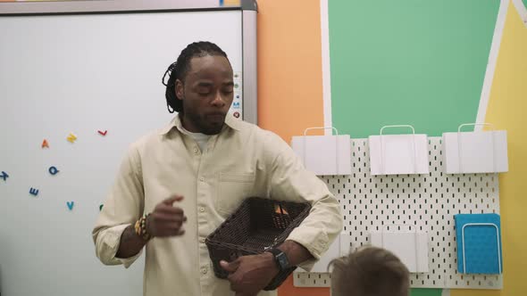 An African American Teacher and a Group of Children are Studying Fruits and Animals in the Classroom