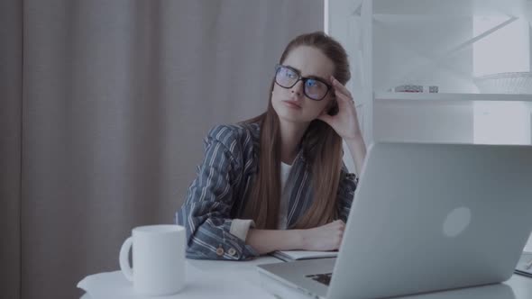 Serious Girl Tired After Work and Takes Her Glasses Off at the Office