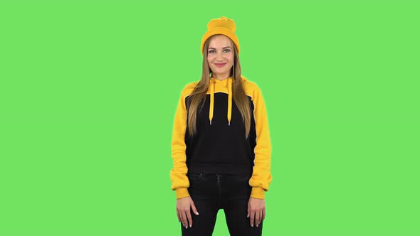 Modern Girl in Yellow Hat Is Waving Hand Hi Then Blowing Kiss. Green Screen