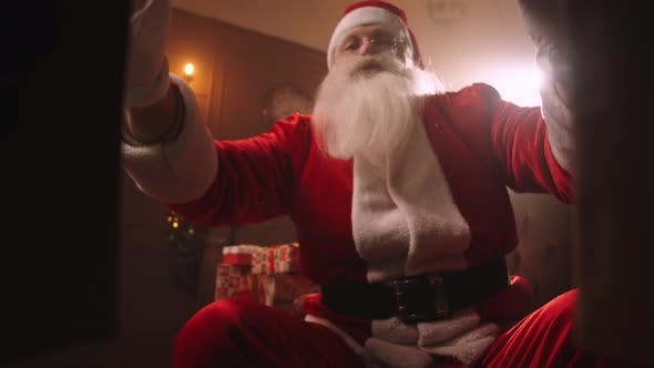 Old Person Dressed Santa Claus Suit Is Opening Box with Gift in Decorated Room at Holiday Evening