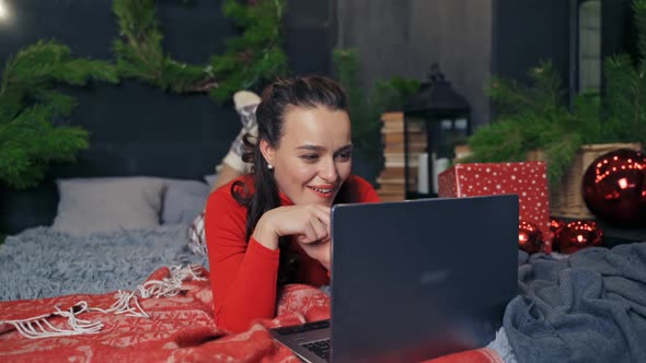 Woman lying on bed with laptop. Beautiful girl lying on bed with laptop computer