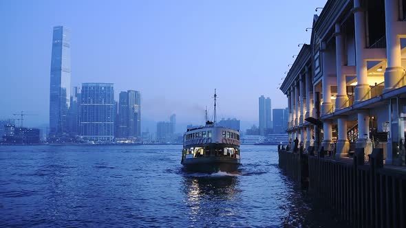 Star Ferry Boat Arriving At Kowloon Pier With Hong Kong Central Skyline On The Background At Night. 