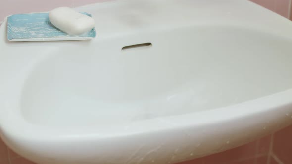 Hand cleaning a bathroom sink with brush