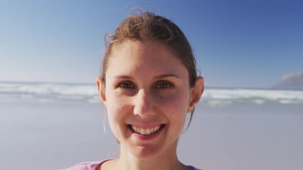 Caucasian woman looking at camera and smiling on the beach and blue sky background