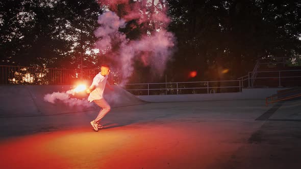 Young Guy is Holding Glowing Red Signal Flare Jumping and Spinning While Performing Breakdance on