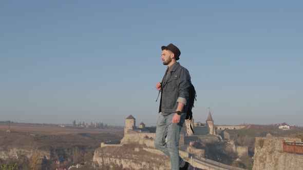 Man Traveler with Backpack Explores the City Looking at the Panoramic View of the City and the Coast