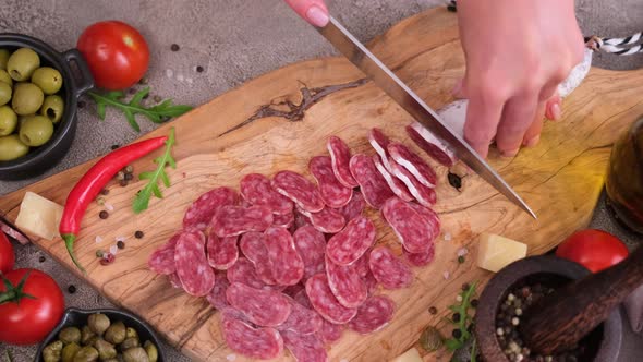 Woman Slicing Fuet Sausage with Knife at Domestic Kitchen