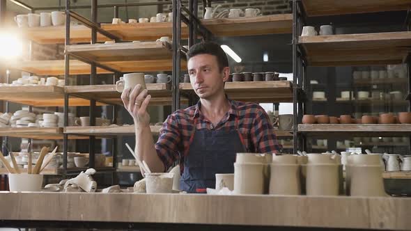 Male Potter Looking to the Handmade Cap During Work Day in the Pottery