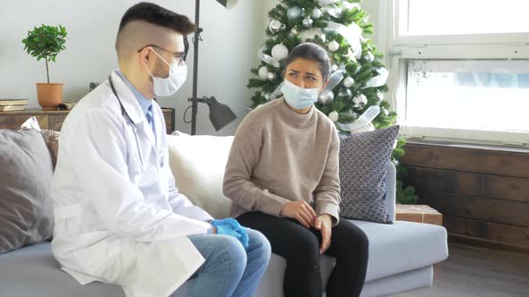 Male doctor in a mask and glasses and a woman in a mask, a sick patient at home. Health visitor