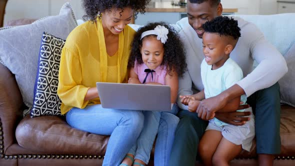 Front view of black family using laptop in living room at home 4k