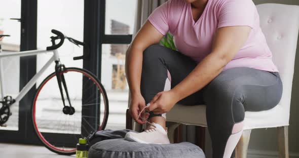 Video of plus size african american woman in sport clothes tying shoes