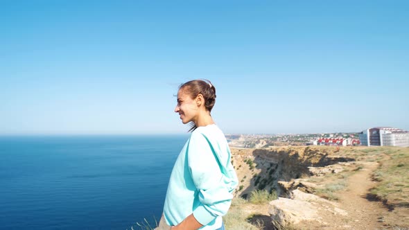 Woman Traveler Stands on Background of Limewall Cliffs and Sky