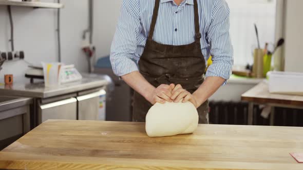 Handsome Male Baker in Black Apron Kneading Dough Making Bread at the Bakery Kithen