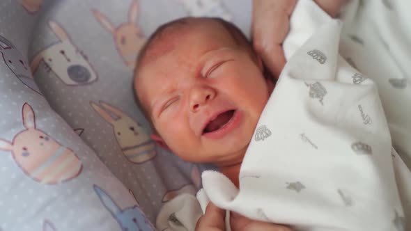 Mom's Hands Straighten the Blanket at the Sleeping in the Crib of the Newborn