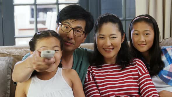 Smiling family watching television together in living room 4k