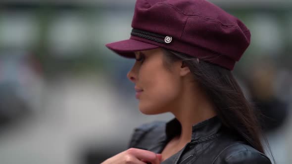 Close-up Portrait of a Beautiful Female Model in a Purple Cap and Leather Jacket Posing in a Public