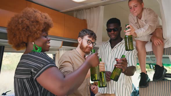 Interracial Group of Cheerful Close Friends Toasting with Beer Bottles Having Drinks to Celebrate a