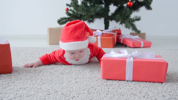 Christmas Concept. Cute Baby in Costume of Santa Claus, Looking a Gift