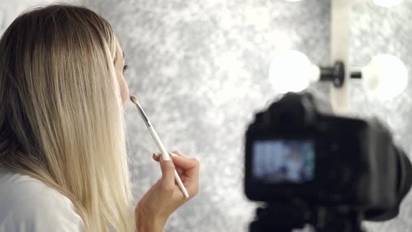 The Pretty Blond Makeup Artist Is Applying Eyeshadow Looking in a Mirror
