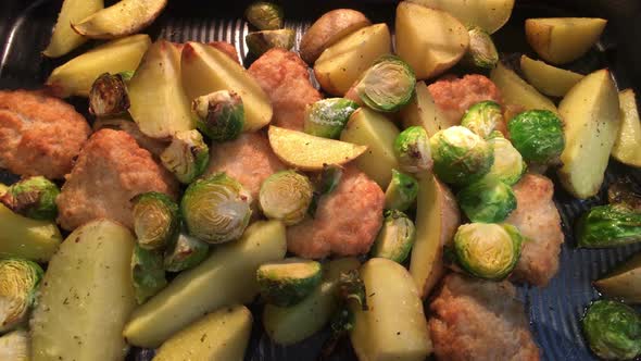 Baked potato with vegetables and baked chicken pieces in the oven