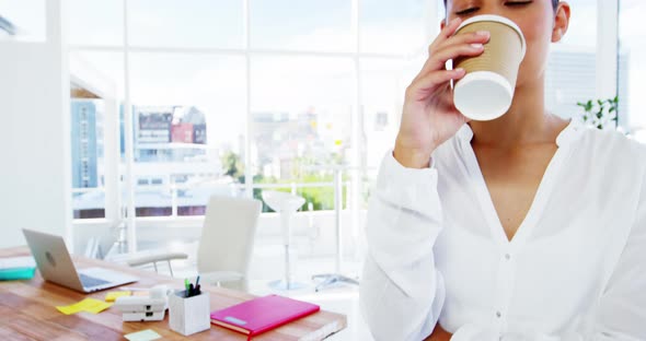 Woman sipping coffee with office background