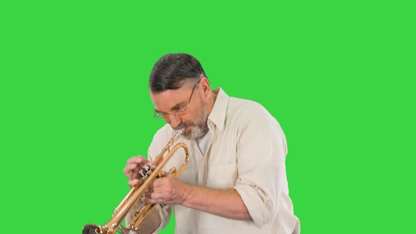 Old Man in Glasses Playing Trumpet on a Green Screen, Chroma Key.