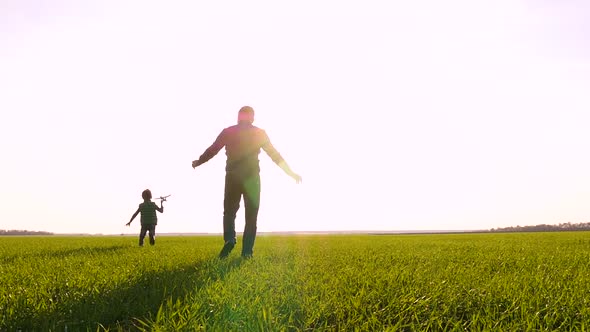 A Happy Father and Son Play with a Toy Airplane, Tossing It Into the Sky. The Family Spends Time