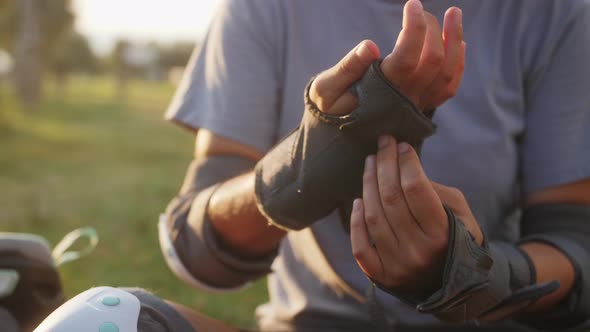 Woman Putting on Wrist Guards and Gloves at the Skate Park to Protect