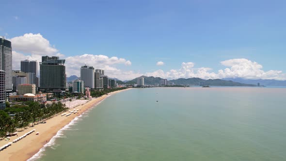 low altitude aerial view of the Nha Trang coastline full of white beach umbrellas on a sunny day wit