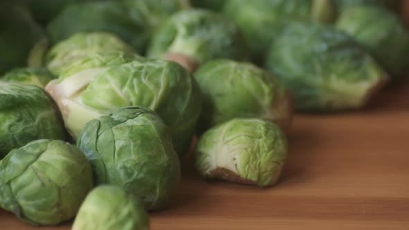 Slow Panning Right to Left on Heap of Raw Brussels Sprouts on Wooden Tabletop