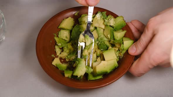 Mashed avocado in a bowl closeup view. Healthy vegan vegetarian food sauce or face mask for you