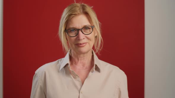 Joyous Senior Woman Posing on Red Background in Studio