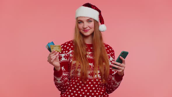 Girl in Christmas Sweater Using Credit Bank Card Smartphone Transferring Money Shopping Online