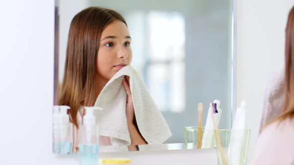 Teenage Girl Wiping Face with Towel at Bathroom