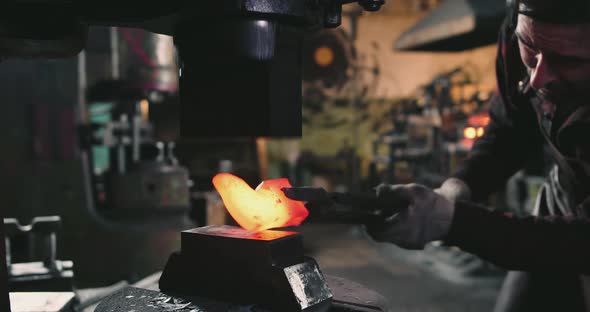 A Blacksmith is Pressing a Metal Blank