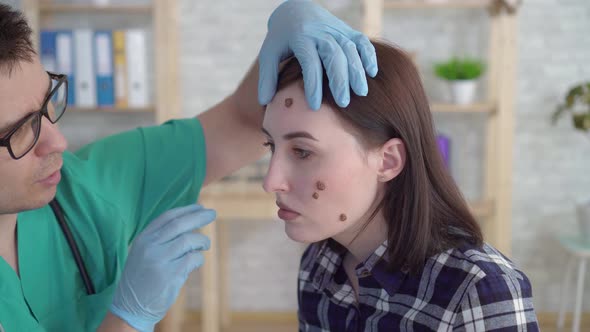 Doctor Examines a Young Woman with Large Moles on Her Face and Gives Recommendations Close Up
