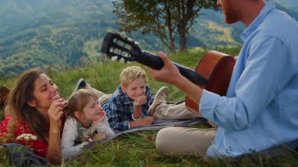 Family Listening Guitar Music on Green Hill