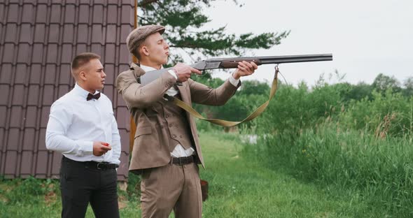 Team of Two Men Shooting the Gun They Wear Old Retro Clothes As Gangsters