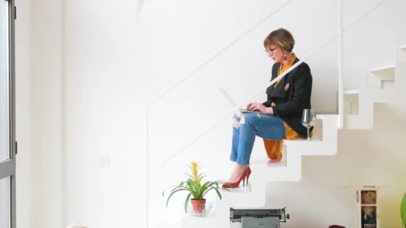 adult woman indoor at home working using laptop computer sitting on the staircase