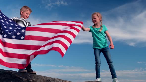 Blonde Boy and Girl Waving National USA Flag Outdoors Over Blue Sky at Summer American Flag Country