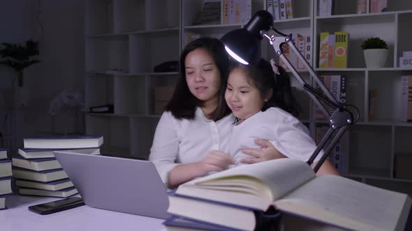 Woman working on laptop at night and kid looking mom working and talking