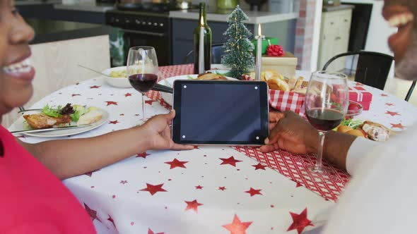 Happy african american senior couple on video call on tablet with copy space at christmas time